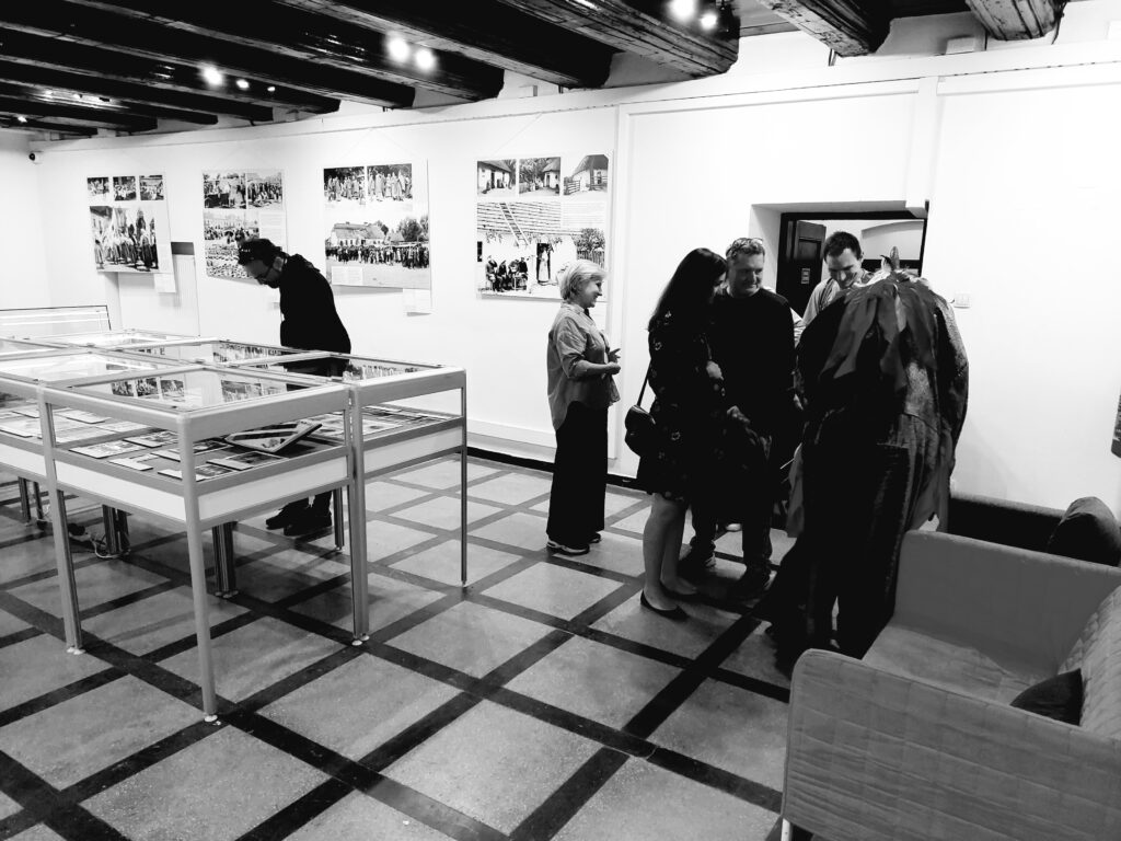 Czarno-biała fotografia odwiedzających i pracowników APW pod modrzewiowym stropem.