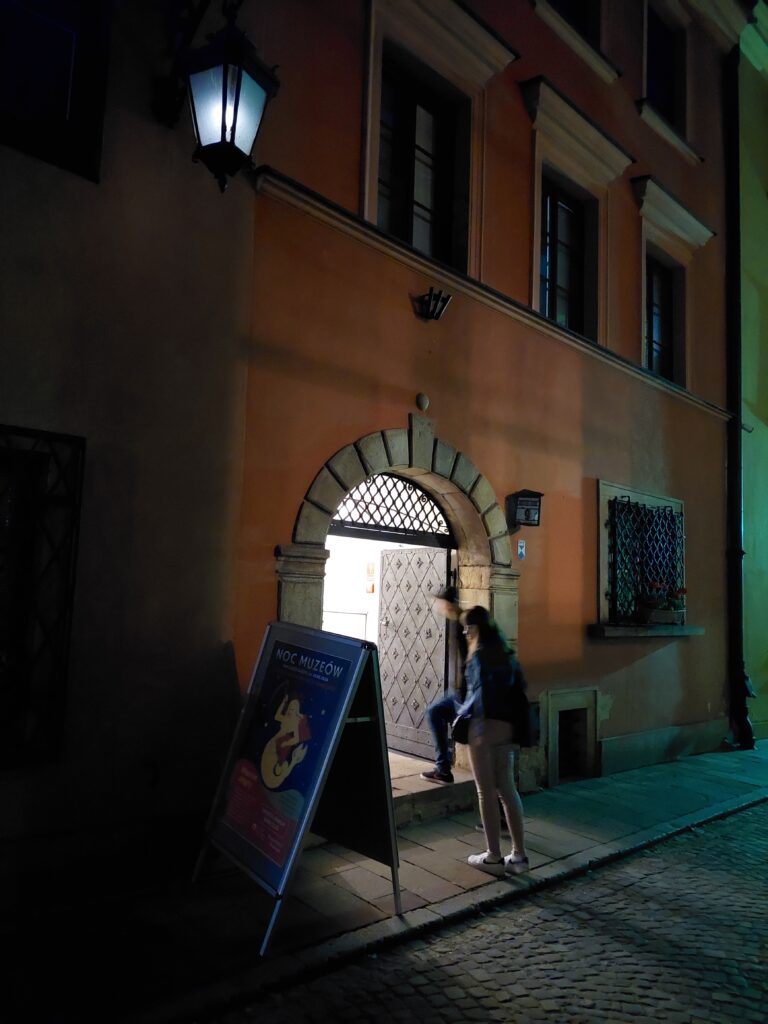 Kobieta w bramie do APW nocą.