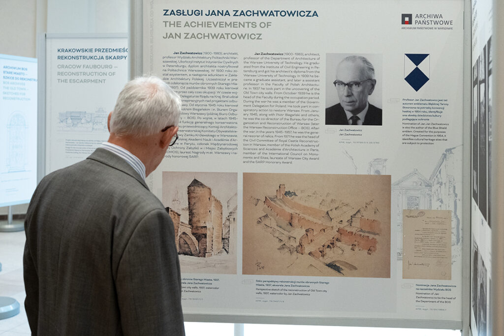 Fotografia starszego mężczyzny odwróconego w kierunku planszy wystawowej