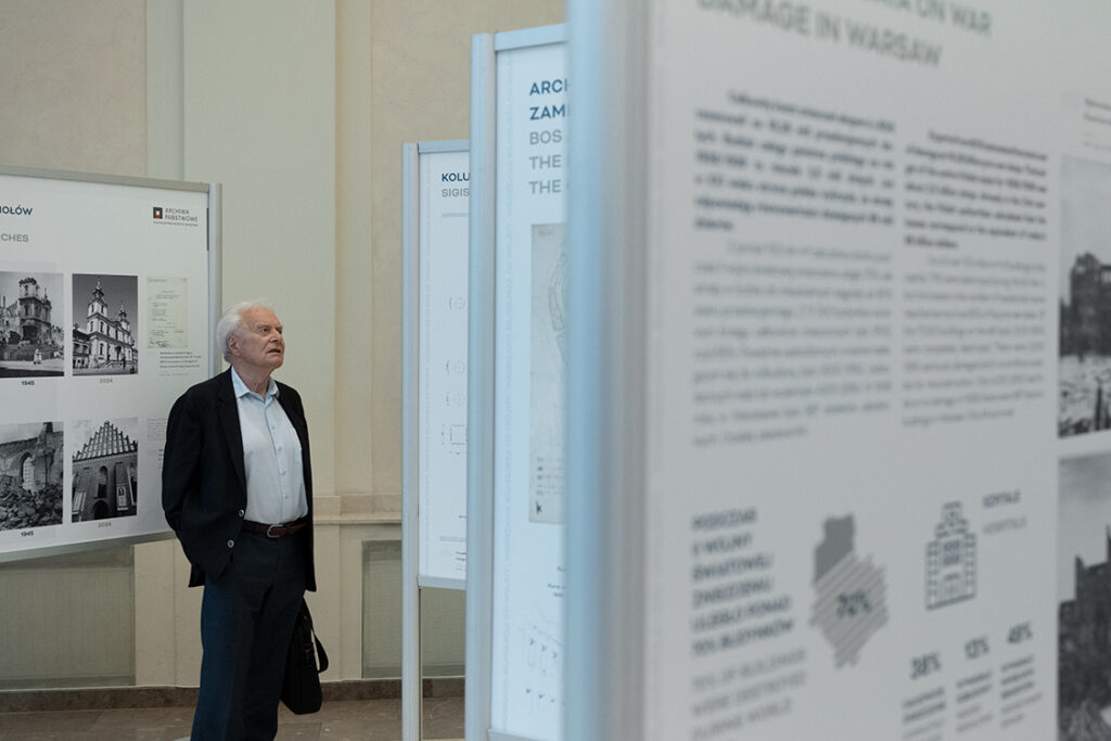 Fotografia starszego mężczyzny stojącego między planszami wystawowymi