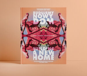 Na kolorowej fotografii widać na tle pomarańczowej ściany książkę z czterema odbiciami lustrzanymi robotnika niosącego taczkę oraz tekstem w języku polskim na okładce.