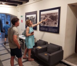 Fotografia kolorowa mężczyzny i kobiety odwróconych tyłem do fotografa, oglądających plansze wystawowe.
