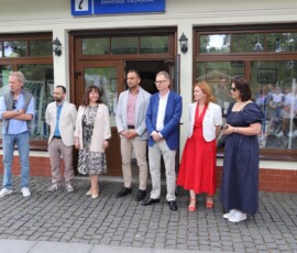 fotografia trzech kobiet i czterech mężczyzn stojących przed witryną budynku