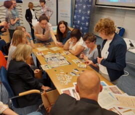 Fotografia osób siedzących przy stole w trakcie w gry planszowej.