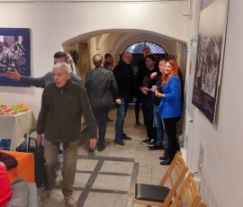 Fotografia kolorowa ludzi zgromadzonych wewnątrz starego budynku.
