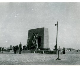 Pomnik Bohaterów Getta przed odsłonięciem, kwiecień 1946 r. Na czarno-białej fotografii widać duży pomnik, pod którym stoi grupa ludzi.