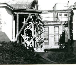 Odbudowa kotłowni Warszawskiej Spółdzielni Mieszkaniowej przy ul. Suzina, wrzesień 1947 r. Na czarno-białej fotografii widać cegły rozbiórkowe oraz zrujnowany budynek podtrzymywany drewnianą konstrukcją.