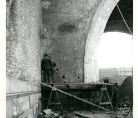 Borowanie otworów do wysadzenia wiaduktu Pancera, luty 1946 r. Na czarno-białej fotografii widać mężczyznę wiercącego dziurę w ścianie wiaduktu.