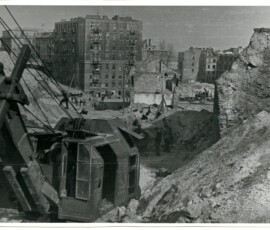 Rozbiórki w rejonie Nowego Zjazdu, kwiecień 1948 r. Na czarno-białej fotografii widać sprzęt budowlany, a tle grupa ludzi i budynki.