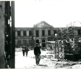 Odbudowa pałacu Potockich przy ul. Krakowskie Przedmieście, lipiec 1948 r. Na czarno-białej fotografii widać trzech mężczyzn, cegły i zrujnowany budynek.