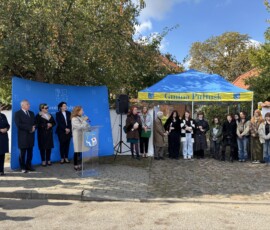 Uczestnicy obchodów Dnia św. Hieronima w Archiwum Państwowym w Warszawie Oddziale w Pułtusku Na zdjęciu widać grupę ludzi przy banerze Gminy Pułtusk oraz grupę młodych dziewcząt pod namiotem z napisem Gmina Pułtusk, w tle drzewa i budynki